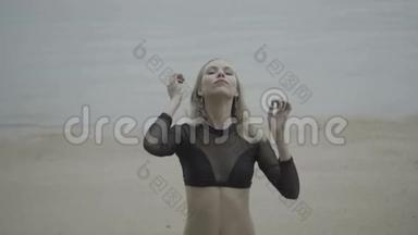 一位身穿黑色优雅泳衣的金发女子在海滩上的正面<strong>景色</strong>，背景是：慢动作<strong>视频</strong>